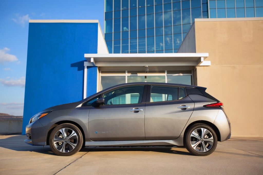 2021 Nissan Leaf parked at a modern building complex. Example of highest electric car depreciation rate.